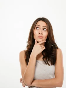 pensive-brunette-woman-holding-her-chin-looking-up-gray